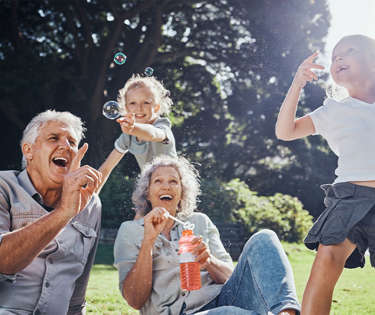 Large-Banner-Homem e mulher idosos brincam com os netos num jardim a fazer bolhas&Mobile-BrincarComCriancas