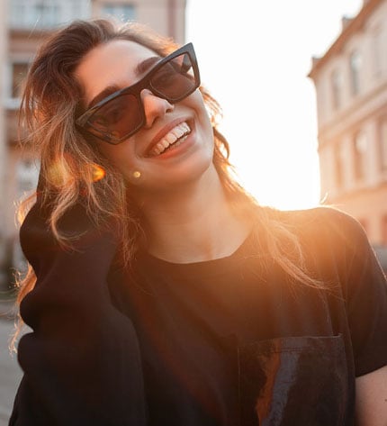 Retrato de rapariga sorridente com óculos de sol ao pôr do sol