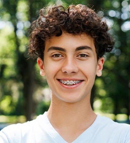 Foto retrato de rapaz com cabelo encaracolado e aparelho nos dentes
