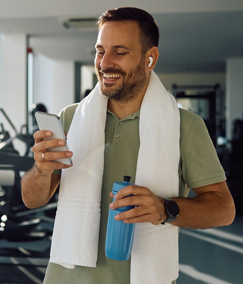 Homem no ginásio ao telemóvel a ouvir música numa passadeira parada