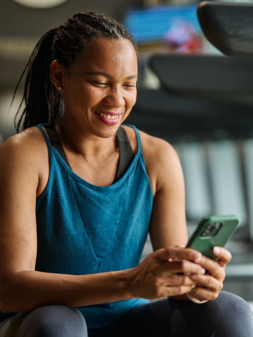 Mulher sentada sorridente com o telemóvel na mão a escrever