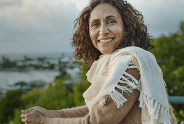 senhora-apoiada-numa-varanda-a-sorrir-com-vista-praia -mobile2