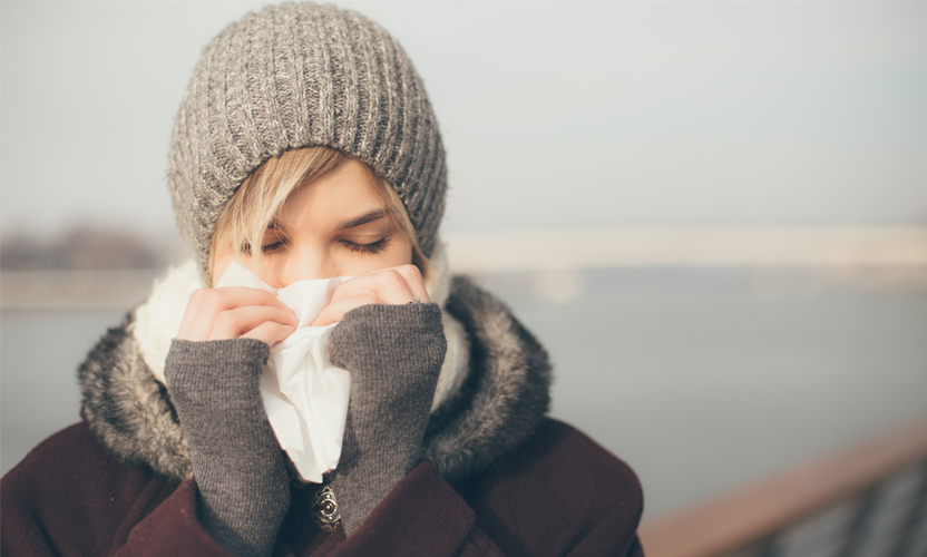 Rapariga constipada a limpar o nariz com lenço de papel