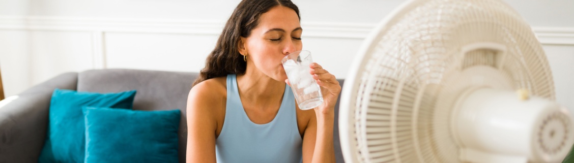 Mulher a beber água em frente a uma ventoinha