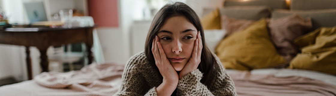 Jovem pensativa com as mãos na cara