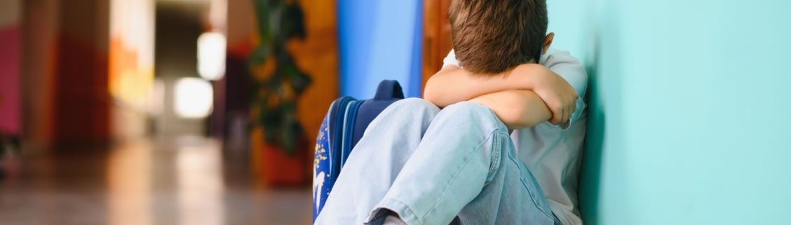 Criança sentada no chão a chorar na escola